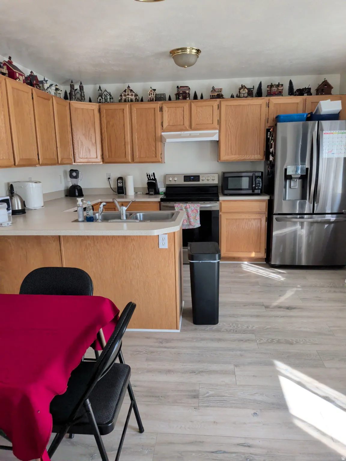 Kitchen featuring abundant wood-finish cabinetry, light-toned countertops, and wood-finish flooring