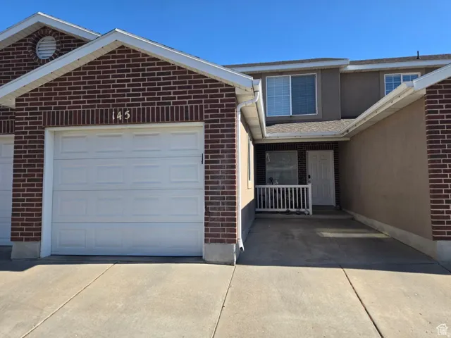 Brick and stucco exterior, white garage door, white railing, concrete driveway, front entrance