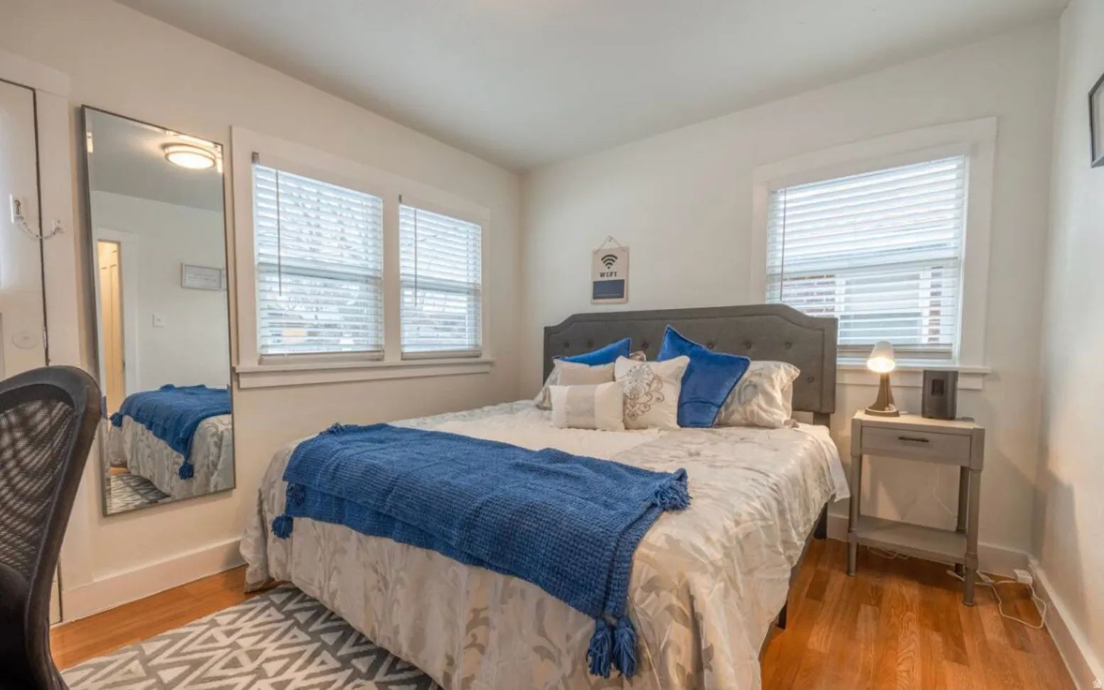 Hardwood flooring, white walls, multiple windows with blinds, and a built-in closet with bifold doors