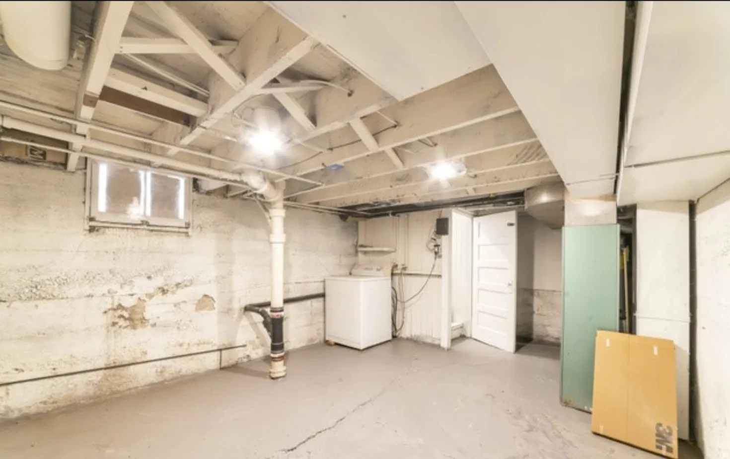 Exposed ceiling joists, painted concrete floor, and whitewashed foundation walls