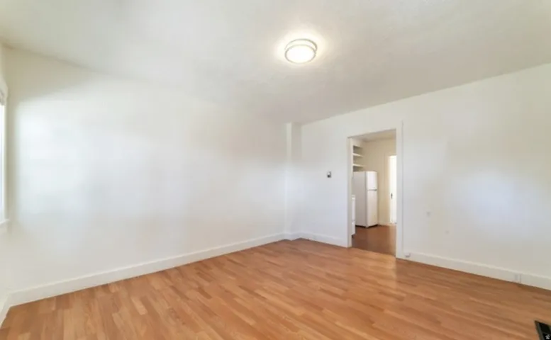 Light wood-finish flooring, white painted walls, and overhead flush-mount lighting