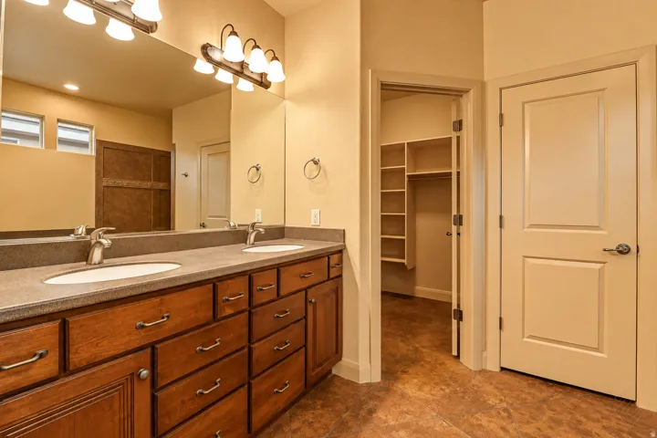 Dual vanity with undermount sinks, wood-finish cabinetry, and a stone-finish countertop