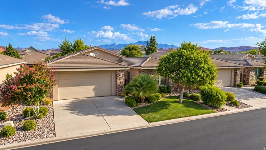 Stucco exterior with stone accents, concrete driveway, and a tiled roof