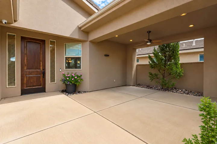 Covered patio with a ceiling fan, recessed lighting, and an accent tree in a rock bed