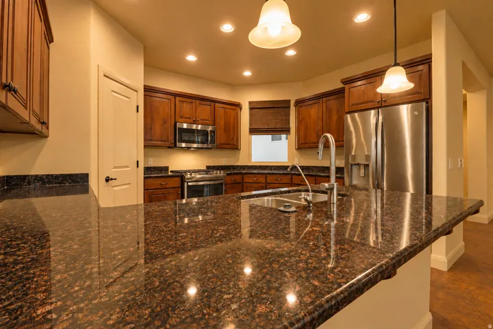 Spacious kitchen with a large island, stainless steel appliances, rich wood cabinetry, and recessed lighting