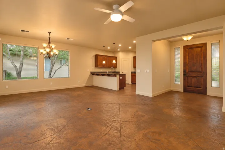 Stamped concrete flooring, recessed lighting, ceiling fan, wood cabinetry, and a substantial wood entry door