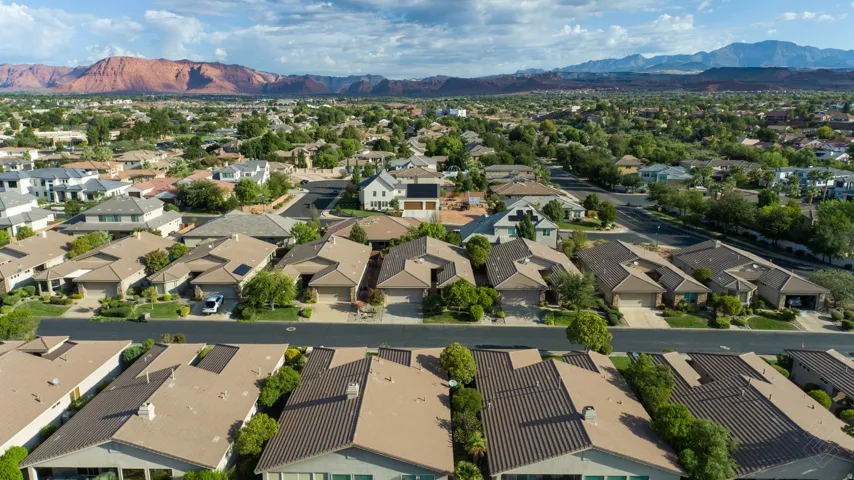 Residential neighborhood with mature trees and paved streets, framed by distant mountains