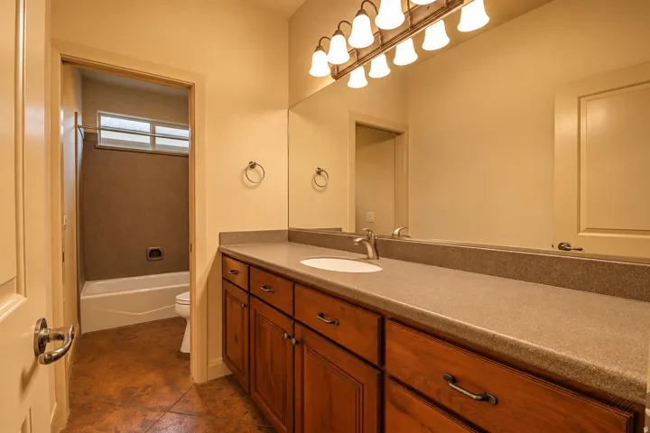 Vanity with a solid surface countertop, an undermount sink, and wood-finish cabinetry