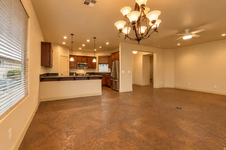 Open-concept living and dining area featuring polished concrete flooring, recessed ceiling lighting, and a central kitchen island with complementary cabinetry