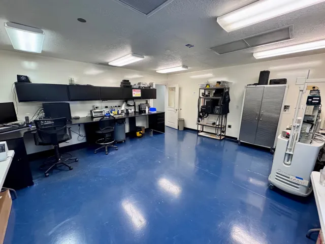 Unit A cleanroom 2-Spacious room featuring a blue finished floor, white walls, and multiple ceiling-mounted light fixtures