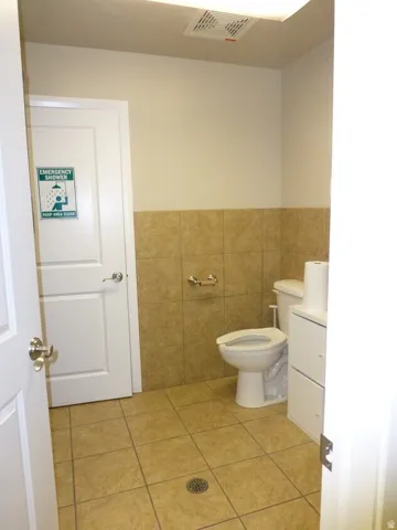 Unit D- Tiled flooring with a floor drain, a white door, and a white toilet