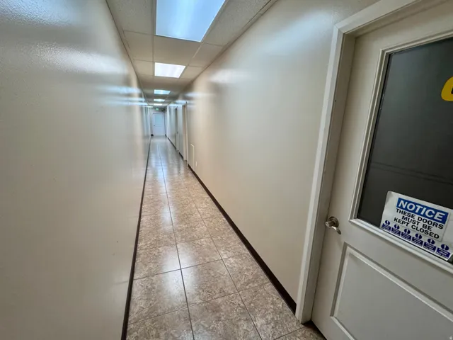 Unit A- Tile with Epoxy grout, Recessed lighting illuminates a long hallway with tile flooring