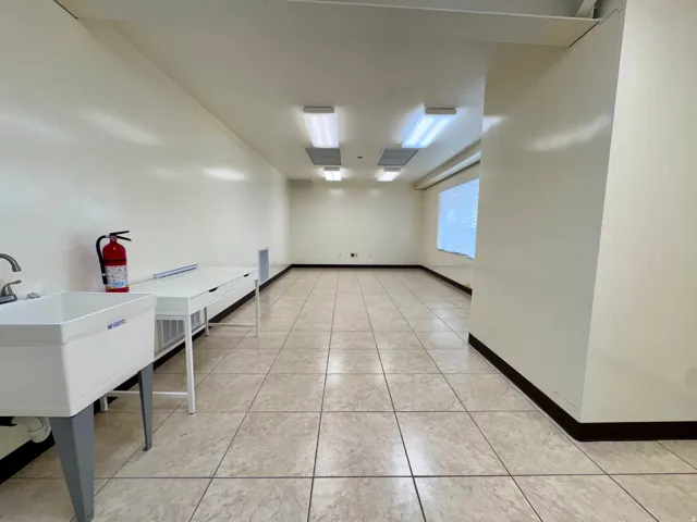 Unit A- Spacious interior featuring tile flooring, a utility sink, and overhead fluorescent lighting