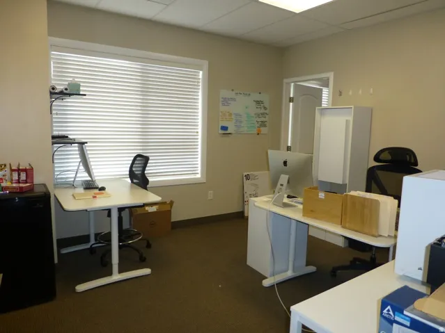 Unit D- Neutral tone wall paint, white trim window, horizontal blinds, brown carpeted flooring, and a white interior door
