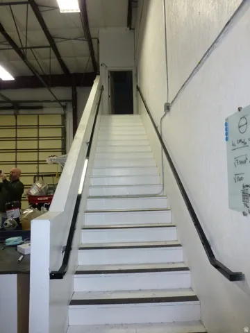 Unit D- Stairwell with painted treads and risers, black anti-slip strips, and wall-mounted handrails