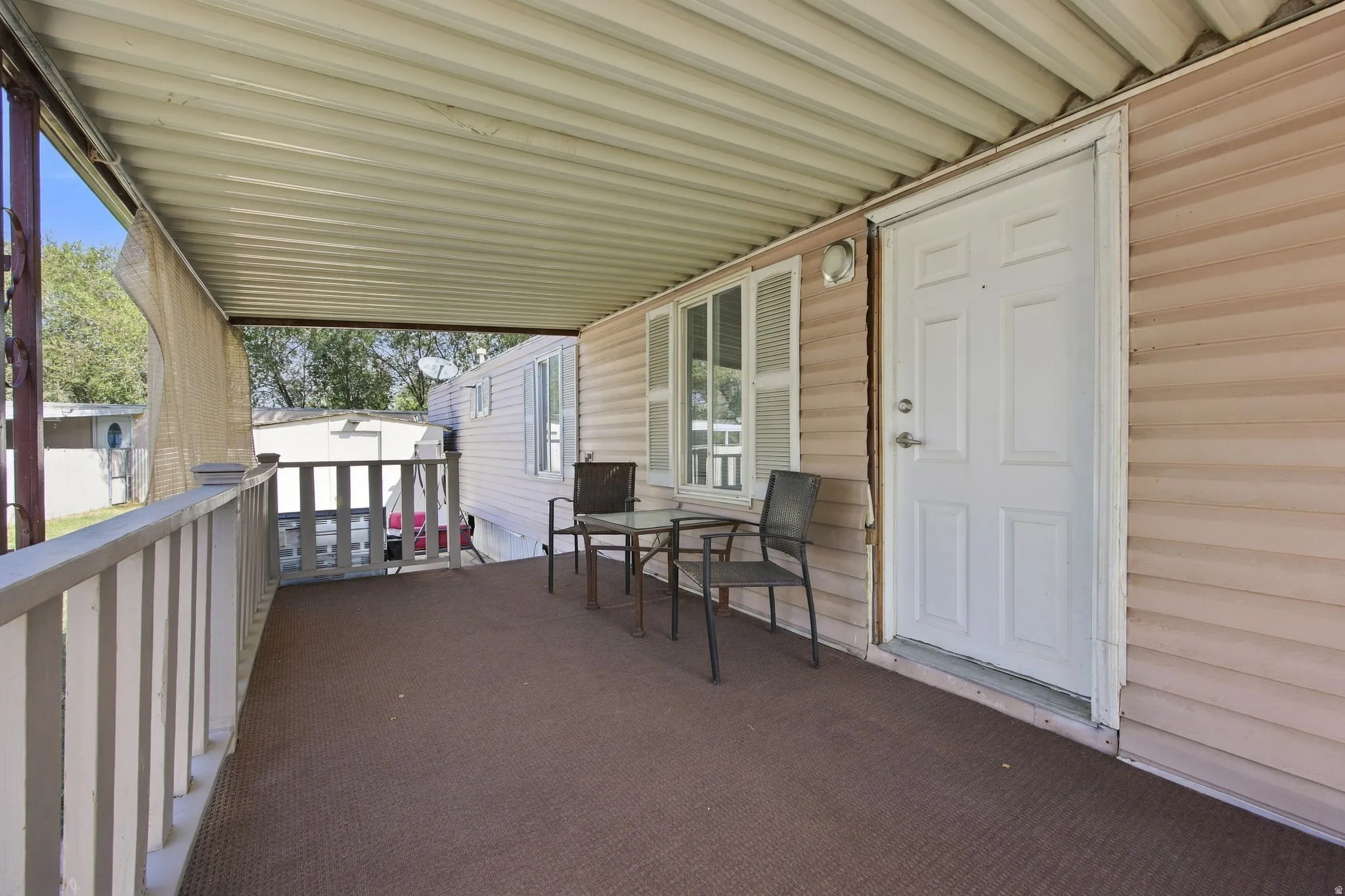 Covered porch area with a corrugated ceiling, wall-mounted light fixture, and horizontal siding