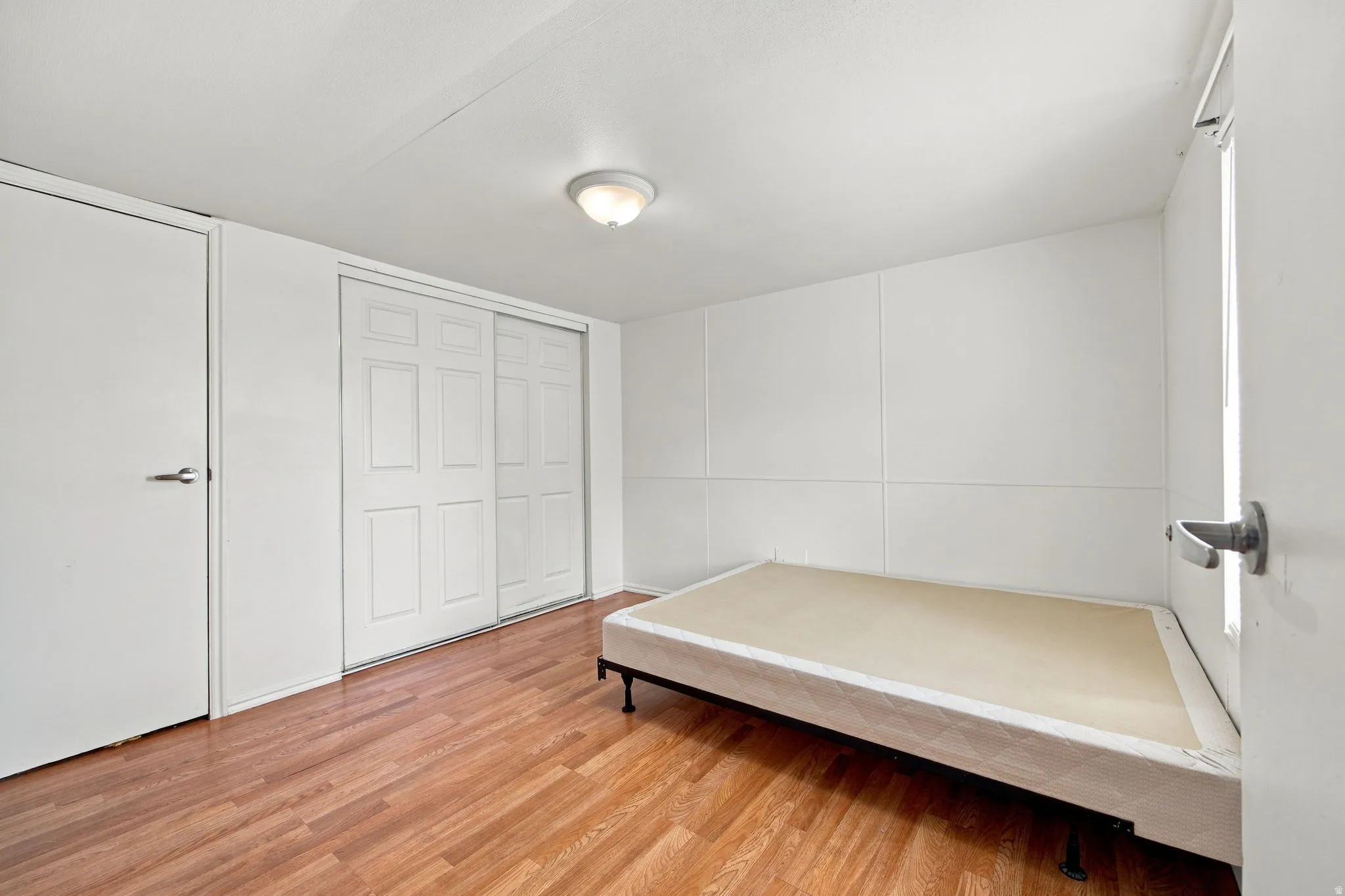 Wood-finish flooring, white walls, and a ceiling-mounted light fixture