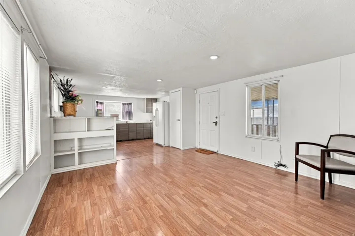 Wood-finish flooring throughout, white walls, built-in shelving, recessed lighting, and multiple windows with blinds