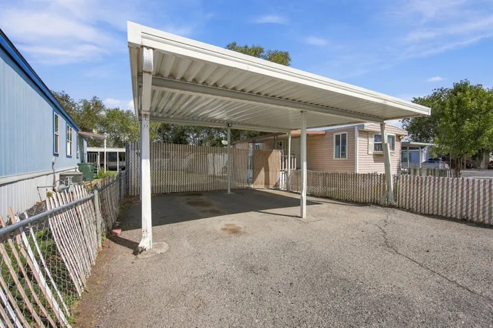 Attached carport with a corrugated roof, offering covered parking