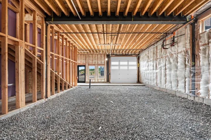 Unfinished interior with exposed wood framing, concrete foundation, and a white garage door