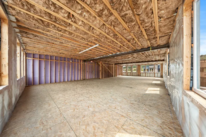 Unfinished interior space featuring exposed wood framing, ceiling insulation, and multiple windows