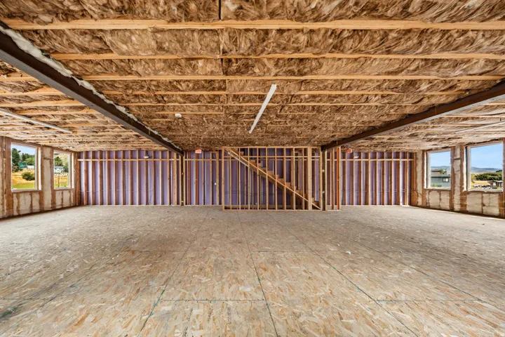 Open-concept space featuring exposed ceiling joists, insulation, and wood subflooring