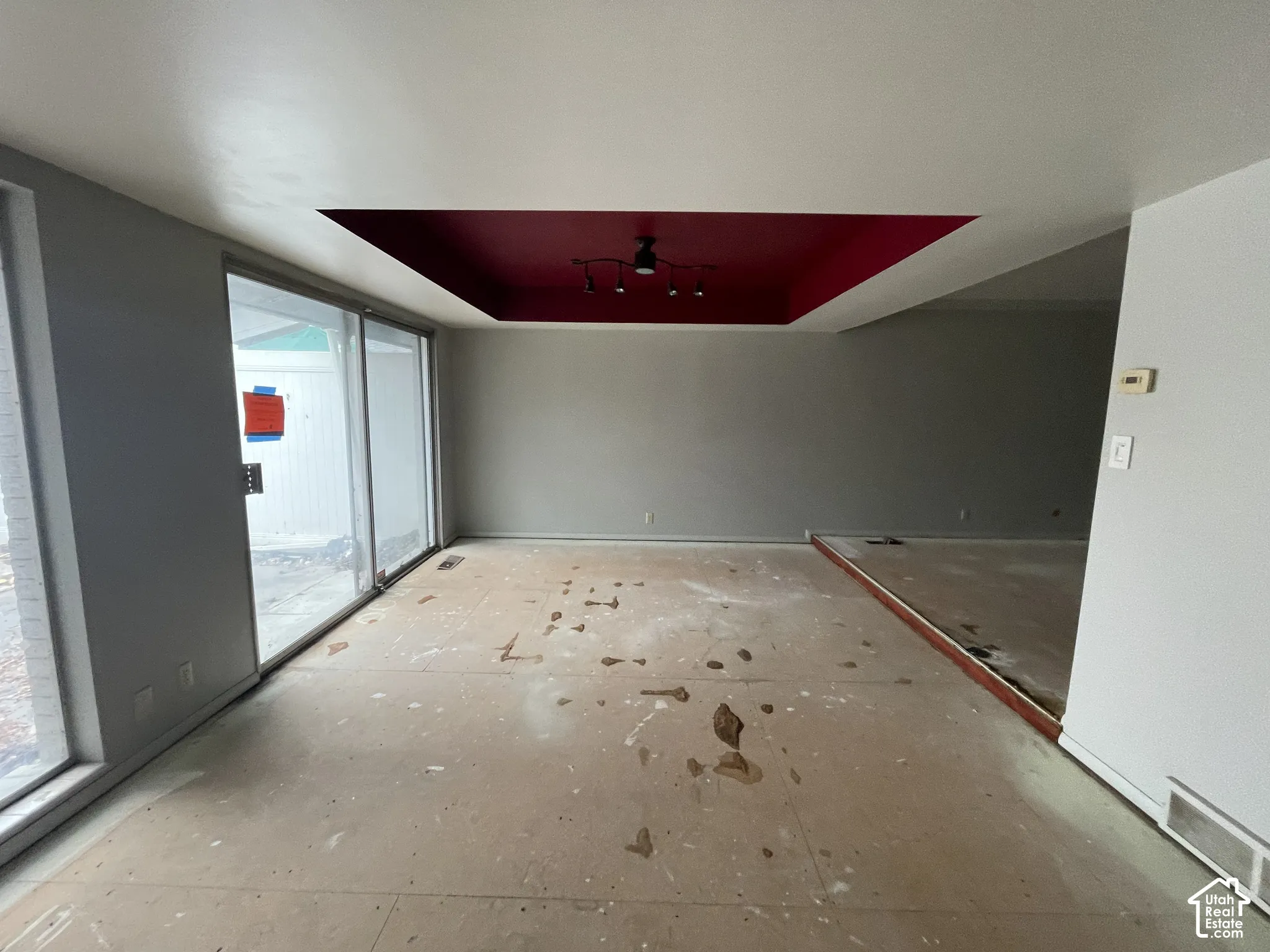 Tray ceiling featuring a recessed center, oversized sliding glass doors, and expansive wall-to-wall floor space