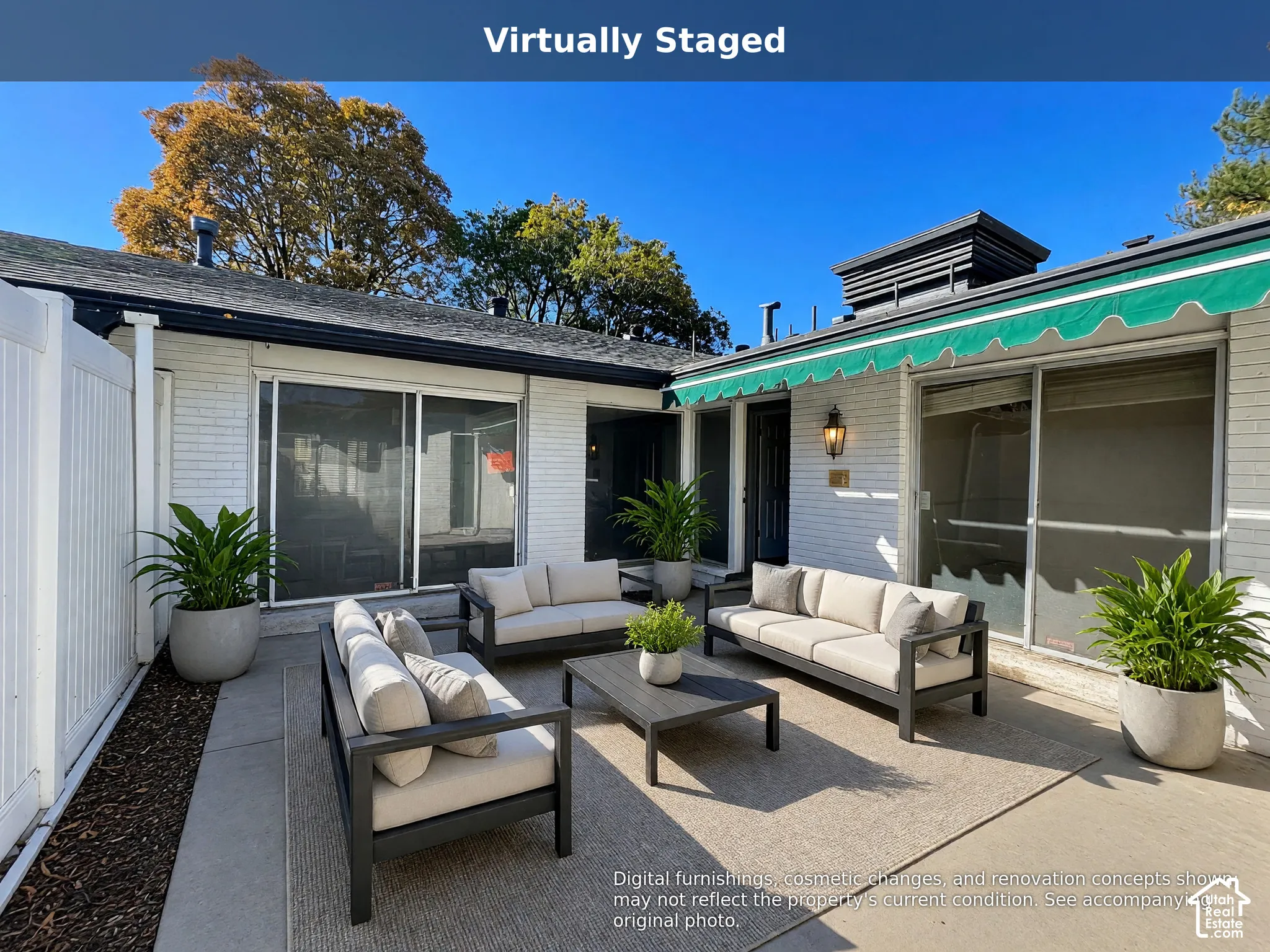 White brick exterior featuring a concrete patio, retractable green awning, and sliding glass doors