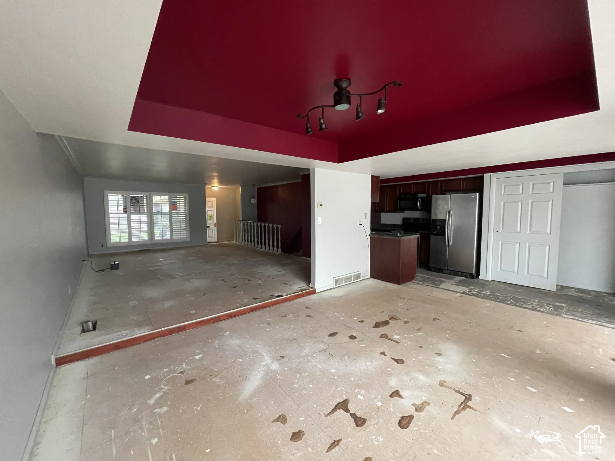 Sunken floor level featuring a recessed tray ceiling with deep red accent finish, multi-directional track lighting, and louvered shutters