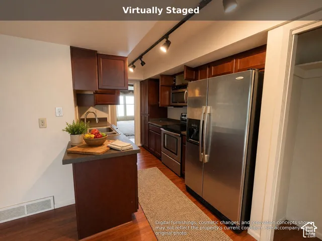 Kitchen featuring dark wood cabinetry, stainless steel appliances, solid surface countertops, a stainless steel sink, and track lighting