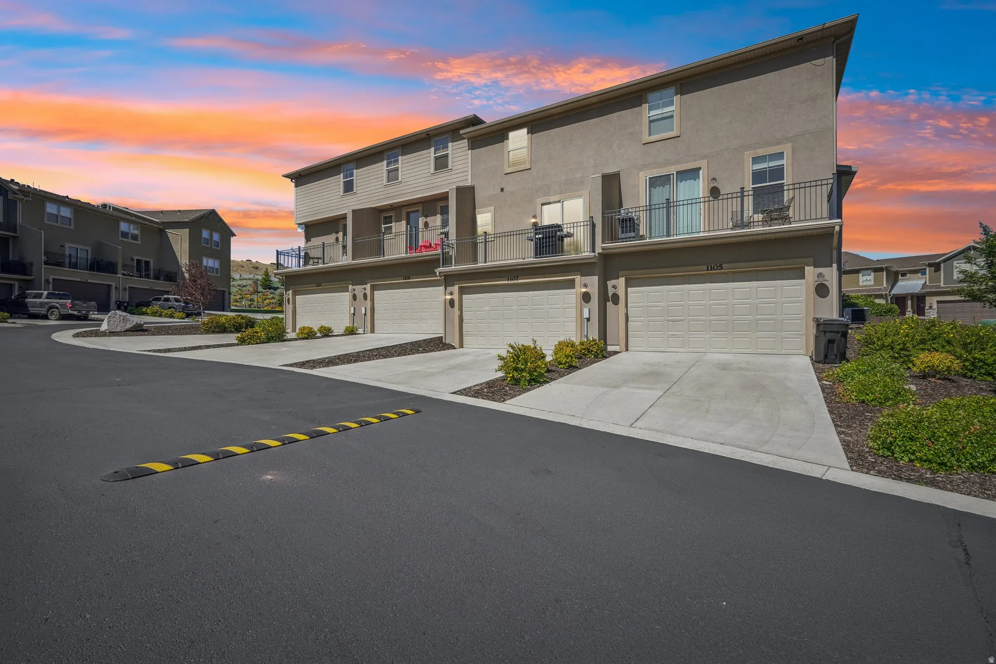 Stucco exterior with multiple attached garages, concrete driveways, and upper-level balconies with black railings