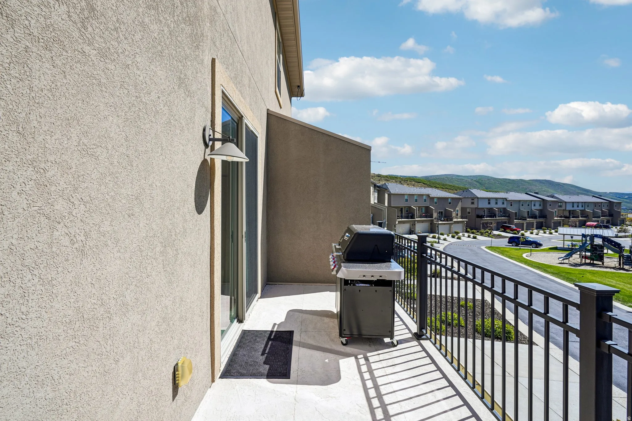 Balcony with stucco exterior, sliding glass door, and black metal railing