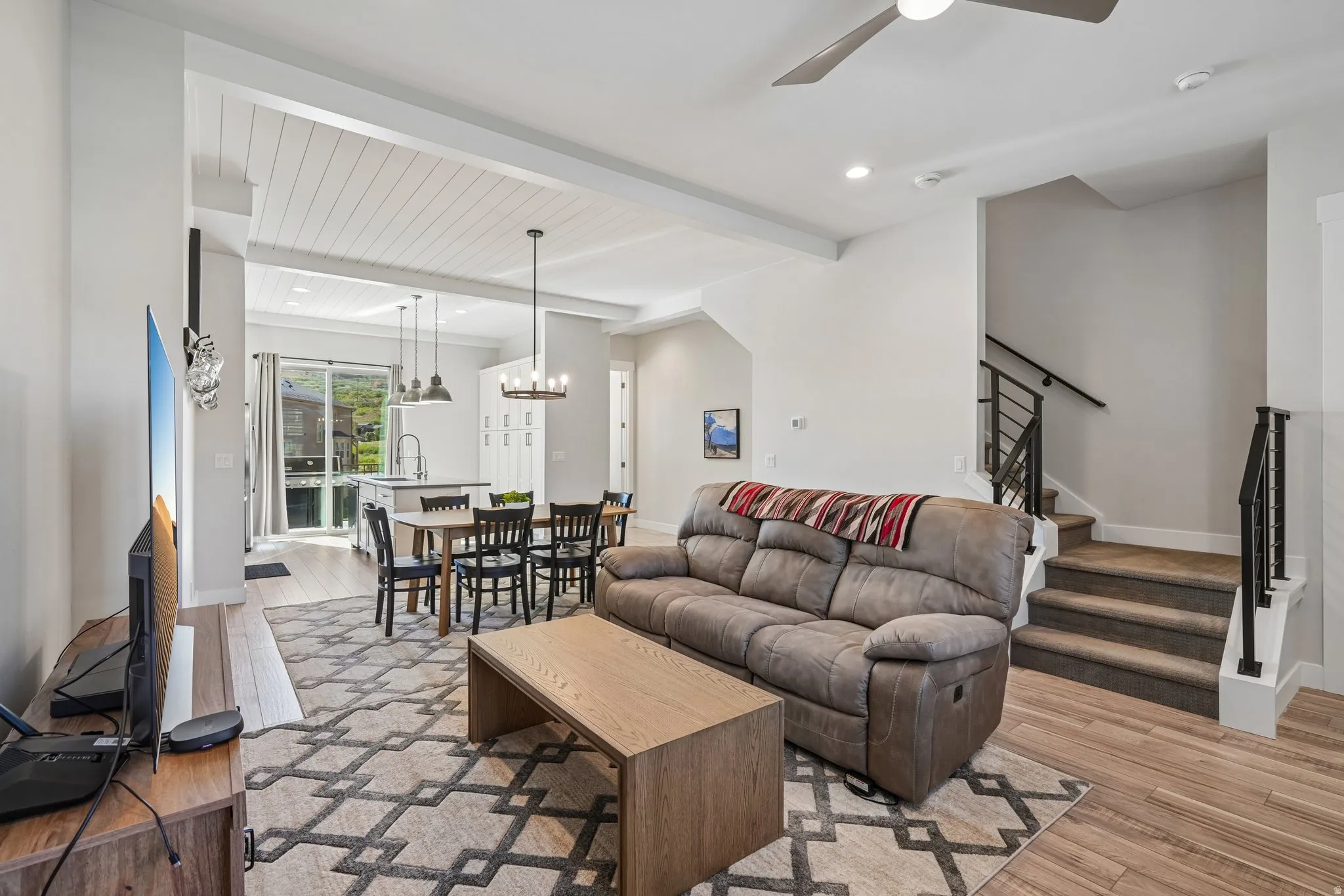 Open-concept living space featuring wood-finish flooring, a shiplap ceiling, and a modern staircase with metal railings