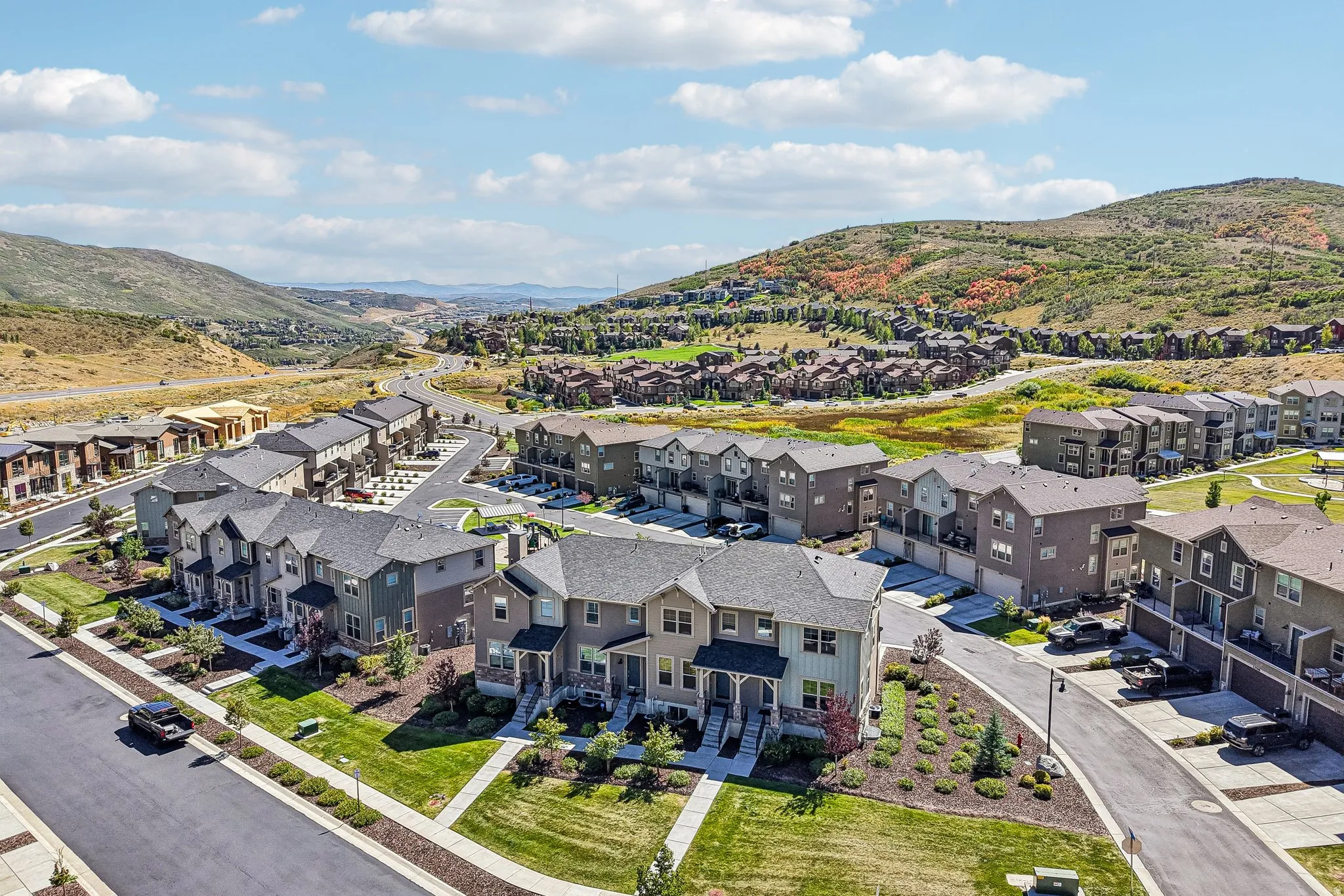 Contemporary residential development featuring multi-story townhomes, paved roadways, and landscaped green spaces