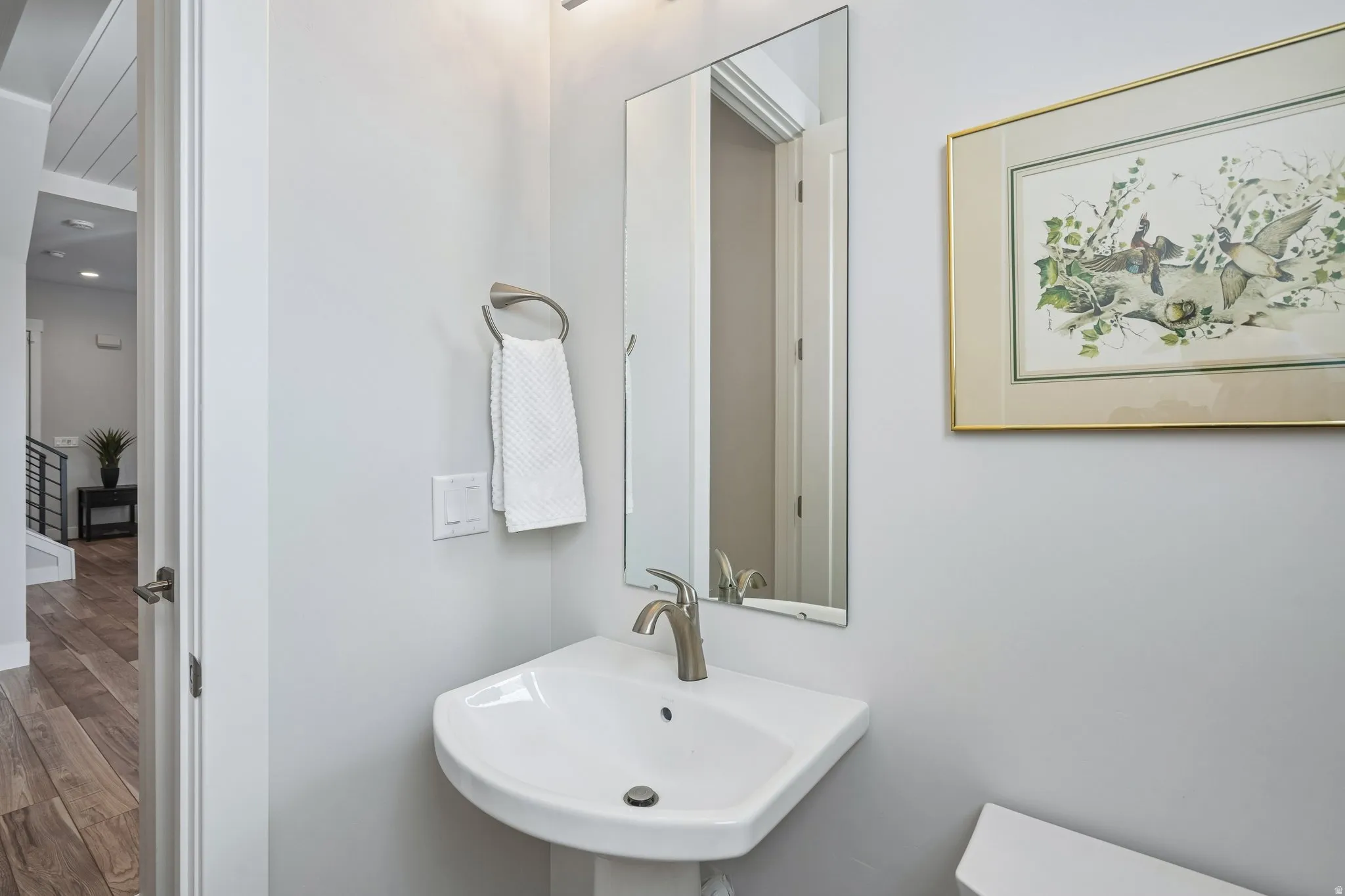 Pedestal sink with a single-handle faucet, rectangular wall mirror, and neutral wall paint