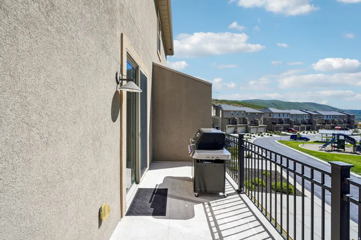 Balcony with stucco exterior, sliding glass door, and black metal railing