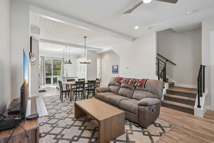 Open-concept living space featuring wood-finish flooring, a shiplap ceiling, and a modern staircase with metal railings