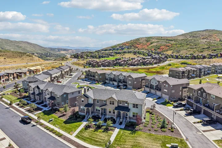 Contemporary residential development featuring multi-story townhomes, paved roadways, and landscaped green spaces