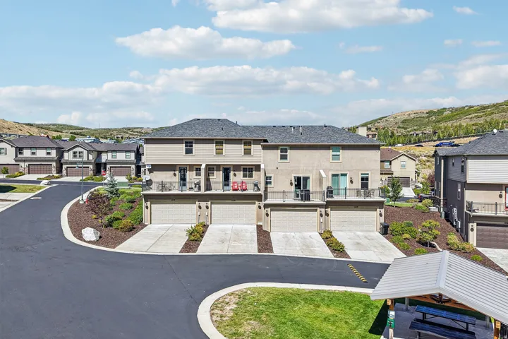 Contemporary townhomes featuring attached garages, private balconies, and sloped rooflines
