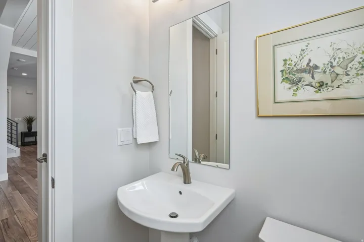 Pedestal sink with a single-handle faucet, rectangular wall mirror, and neutral wall paint