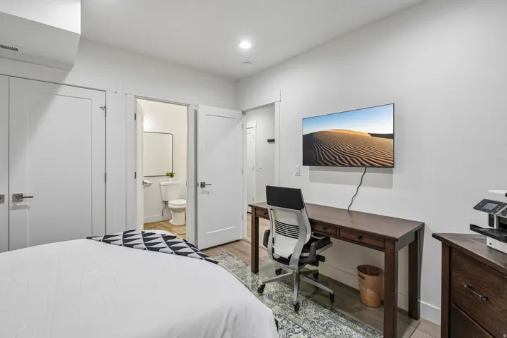 Recessed lighting, wood-finish flooring, white paneled doors with contemporary hardware, and a wall-mounted television