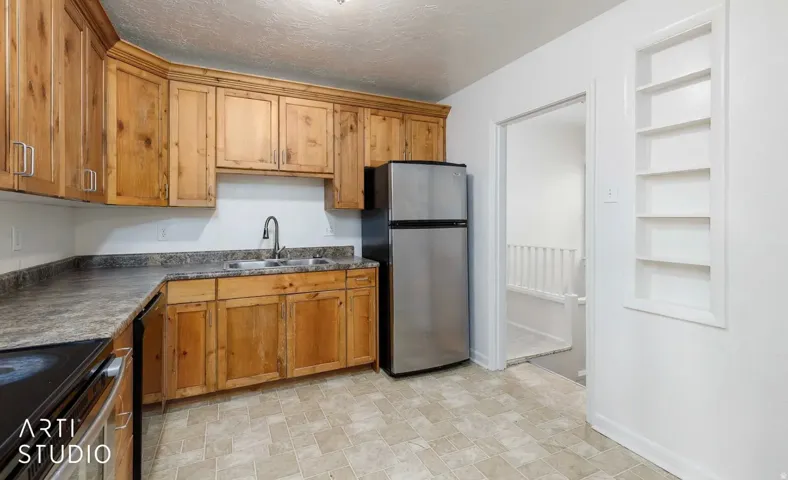Wood cabinetry with brushed nickel hardware, laminate countertops, and a double basin stainless steel sink