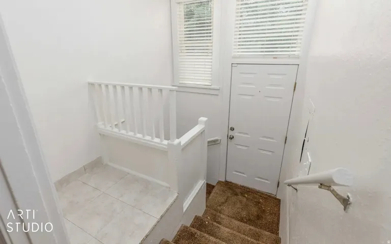 White paneled door with transom window, white window blinds, and white railing