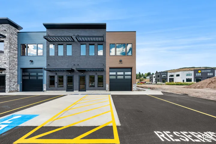 Modern commercial building featuring multiple large windows, a roll-up garage door, and a textured facade
