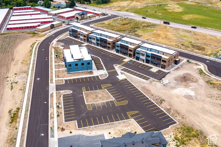 Modern multi-story buildings with varied facades, extensive paved parking, and direct road access