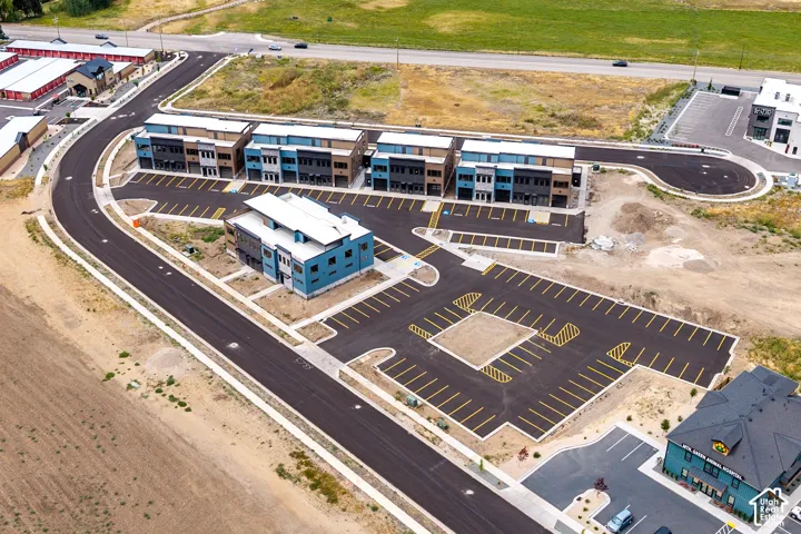 New construction multi-story buildings with contemporary facades, paved roadways, dedicated parking areas, and surrounding undeveloped land
