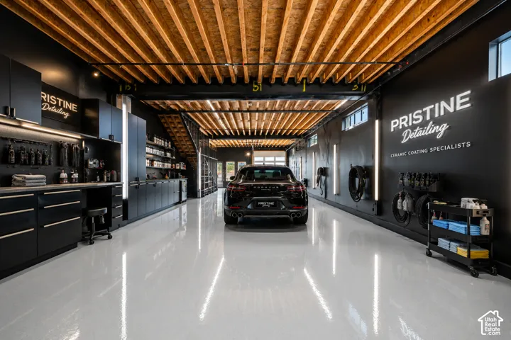 Exposed wood beam ceiling, polished concrete flooring, black cabinetry, built-in shelving, and large exterior doors