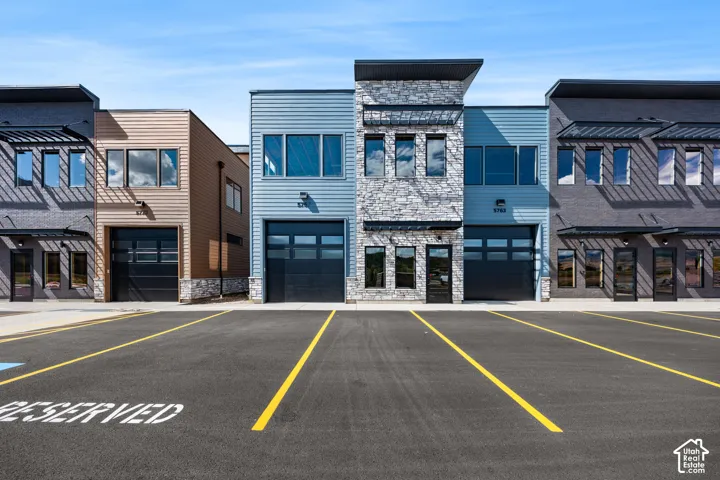 Modern facade with stone and siding accents, prominent garage doors, and multiple large windows