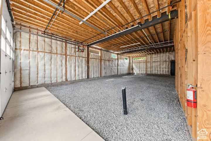 Exposed wood ceiling beams, insulated walls, and gravel flooring