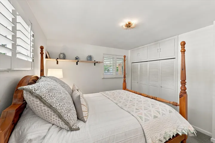 Built-in cabinetry with louvered doors, plantation shutters, and a wall-mounted shelving unit